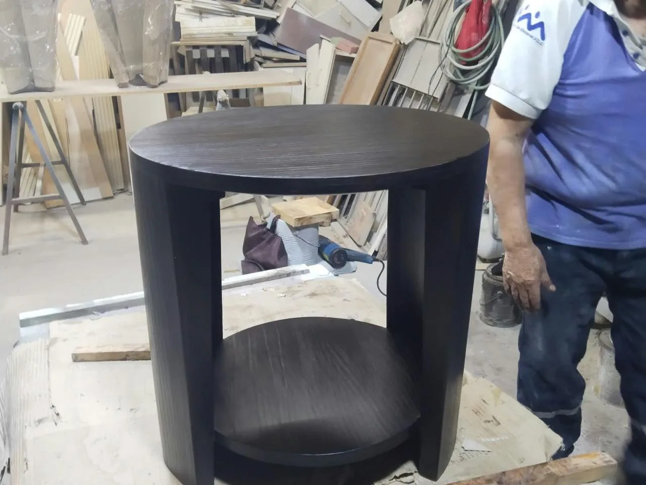 Una mesa terminada en el taller de Breña, junto al operario que la acabó